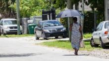 Una donna usa un ombrello per l'ombra quando cammina in una calda giornata a Miami.