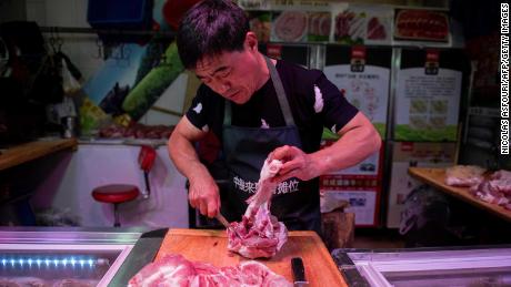 In questa foto scattata il 10 luglio 2019, un macellaio taglia un pezzo di maiale nella sua bancarella in un mercato di Pechino.