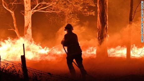 Un pompiere spruzza alberi e braci volanti dagli incendi boschivi nel Nuovo Galles del Sud.
