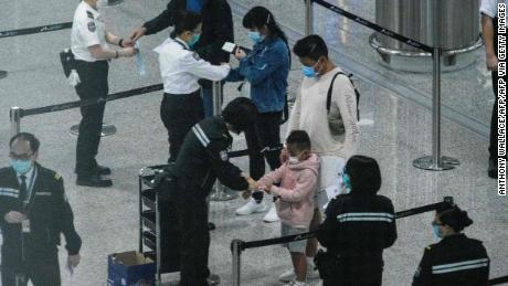 I passeggeri ricevono i braccialetti di localizzazione in quarantena all'aeroporto internazionale di Hong Kong il 19 marzo.