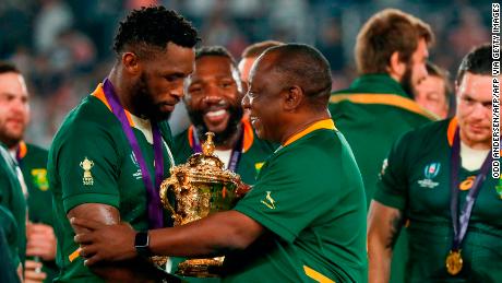 Il presidente sudafricano Cyril Ramaphosa (C) si congratula con il fiancheggiante sudafricano Siya Kolisi (L) mentre celebrano la vittoria della Coppa del mondo di rugby 2019.