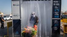 Una persona che indossa una maschera protettiva spinge un carrello della spesa attraverso una camera di decontaminazione nel mercato centrale di frutta e verdura di La Vega a Santiago del Cile.