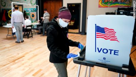 Un lavoratore elettorale del Wisconsin pulisce una cabina elettorale dopo il suo utilizzo il 7 aprile a Madison. Lo stato ha tenuto le sue elezioni sotto un ordine di domicilio. 