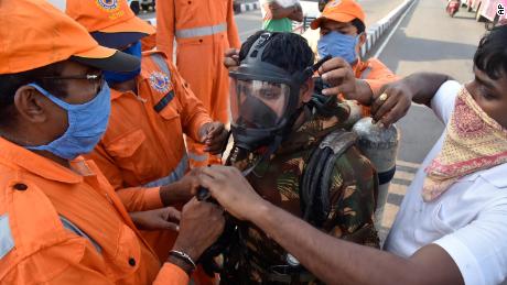 Un membro della National Disaster Assistance Response Force (NDRF) dell'India è equipaggiato con dispositivi di protezione prima di entrare nell'area colpita dalla perdita.