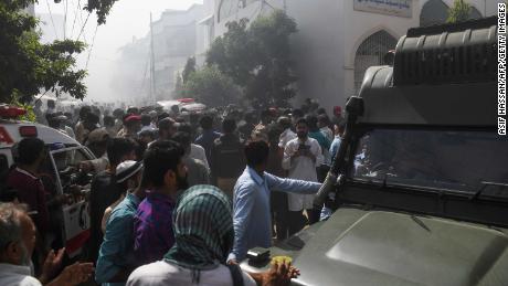 I soccorritori e gli astanti si sono radunati vicino al luogo dell'incidente aereo a Karachi venerdì.