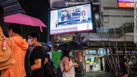 I pedoni camminano sotto uno schermo televisivo a Hong Kong il 21 maggio 2023, mostrando una notizia di Pechino trasmessa dal presidente cinese Xi Jinping (C) alla Conferenza consultiva politica del popolo cinese.