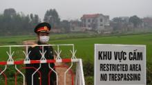 Un ufficiale dell'esercito popolare vietnamita si trova accanto a un segnale di avvertimento riguardante la preclusione del comune di Son Loi nella provincia di Vinh Phuc il 20 febbraio.