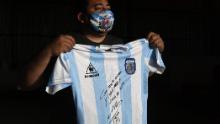 Un uomo detiene una replica della maglia della squadra di calcio argentina utilizzata nella finale della Coppa del Mondo del 1986 e firmata da Diego Maradona.