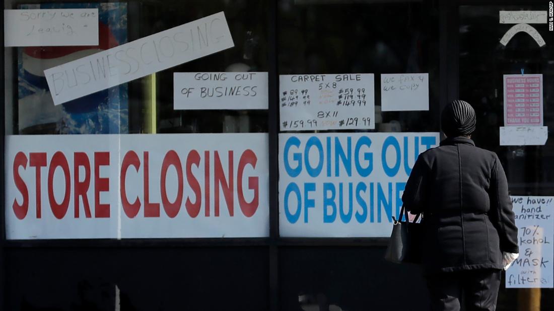 A woman looks at signs at a store closed due to COVID-19 in Niles, Ill., Wednesday, May 13, 2023. (AP Photo/Nam Y. Huh)