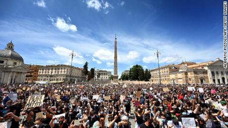 I manifestanti si inginocchiano con segni a Roma.
