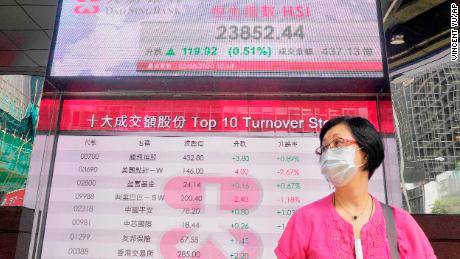 Martedì una donna che indossa una maschera passa davanti a un tavolo bancario elettronico che mostra l'indice azionario di Hong Kong alla Borsa di Hong Kong.