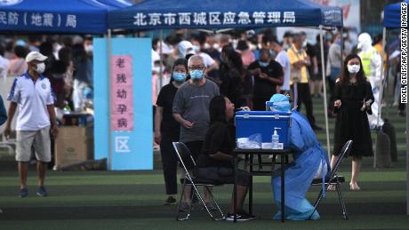 Un operatore sanitario che indossa una tuta protettiva viene sottoposto a un test di tampone di una donna in un centro di prova allestito per le persone che hanno visitato o vivono vicino al mercato Xinfadi di Pechino.