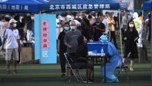 Un operatore sanitario che indossa una tuta protettiva viene sottoposto a un test di tampone di una donna in un centro di prova allestito per le persone che hanno visitato o vivono vicino al mercato Xinfadi di Pechino.