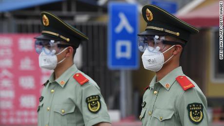 Gli agenti di polizia paramilitari indossano maschere e occhiali mentre fanno la guardia all'ingresso del mercato chiuso di Xinfadi a Pechino il 13 giugno.