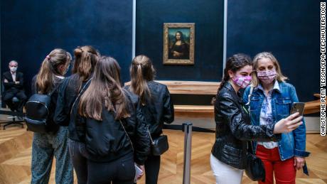 Visitors wearing face masks take photographs in front of the Mona Lisa at the Louvre Museum in Paris on July 6.