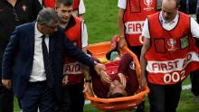 Cristiano Ronaldo è confortato dall'allenatore del Portogallo Fernando Santos mentre viene trasportato su una barella fuori dal campo durante la finale di Euro 2016.