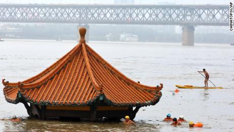 Gli abitanti nuotano davanti a un padiglione sul fiume sommerso dall'allagamento del fiume Yangtze a Wuhan, nella provincia di Hubei, nella Cina centrale, l'8 luglio.