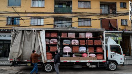 I dipendenti di Bergut Funeral Services consegnano bare a una casa funeraria a Santiago, in Cile, il 19 giugno 2023. La produzione di bare è aumentata del 120%, secondo il proprietario Nicolas Bergerie.