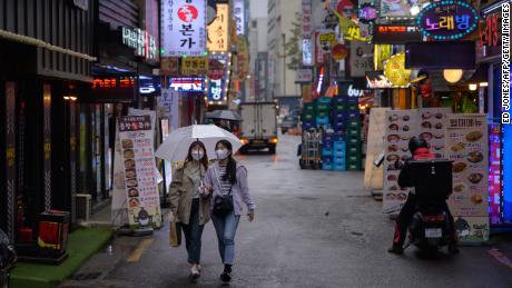 Due donne indossano maschere per il viso a Seoul.  I paesi in cui la copertura del viso è una norma sociale generalmente vanno meglio durante la pandemia.